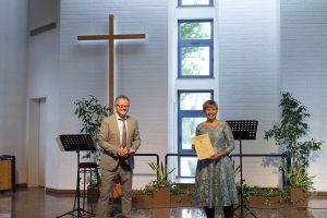 Pastor Hendrik Kissel überreicht Maike Böhl die Ordination-Urkunde
